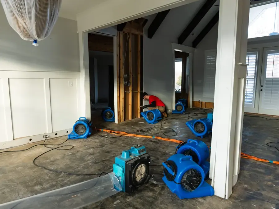An Arlington, VA restoration technician setting air movers to dry a water damaged room